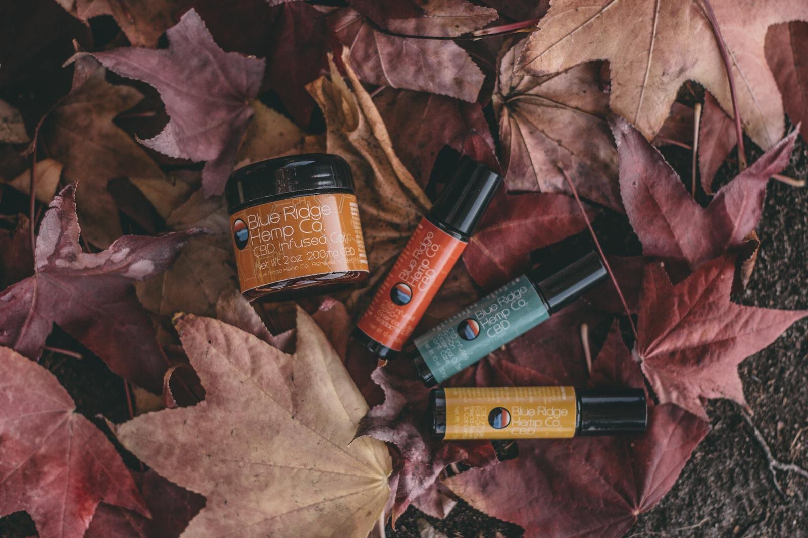 Blue Ridge Hemp Co. CBD infused gel and roll-ons displayed on autumn leaves.