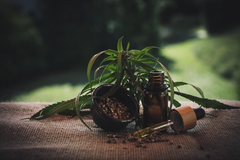 CBD oil bottle with hemp seeds and fresh cannabis leaves on a rustic table.