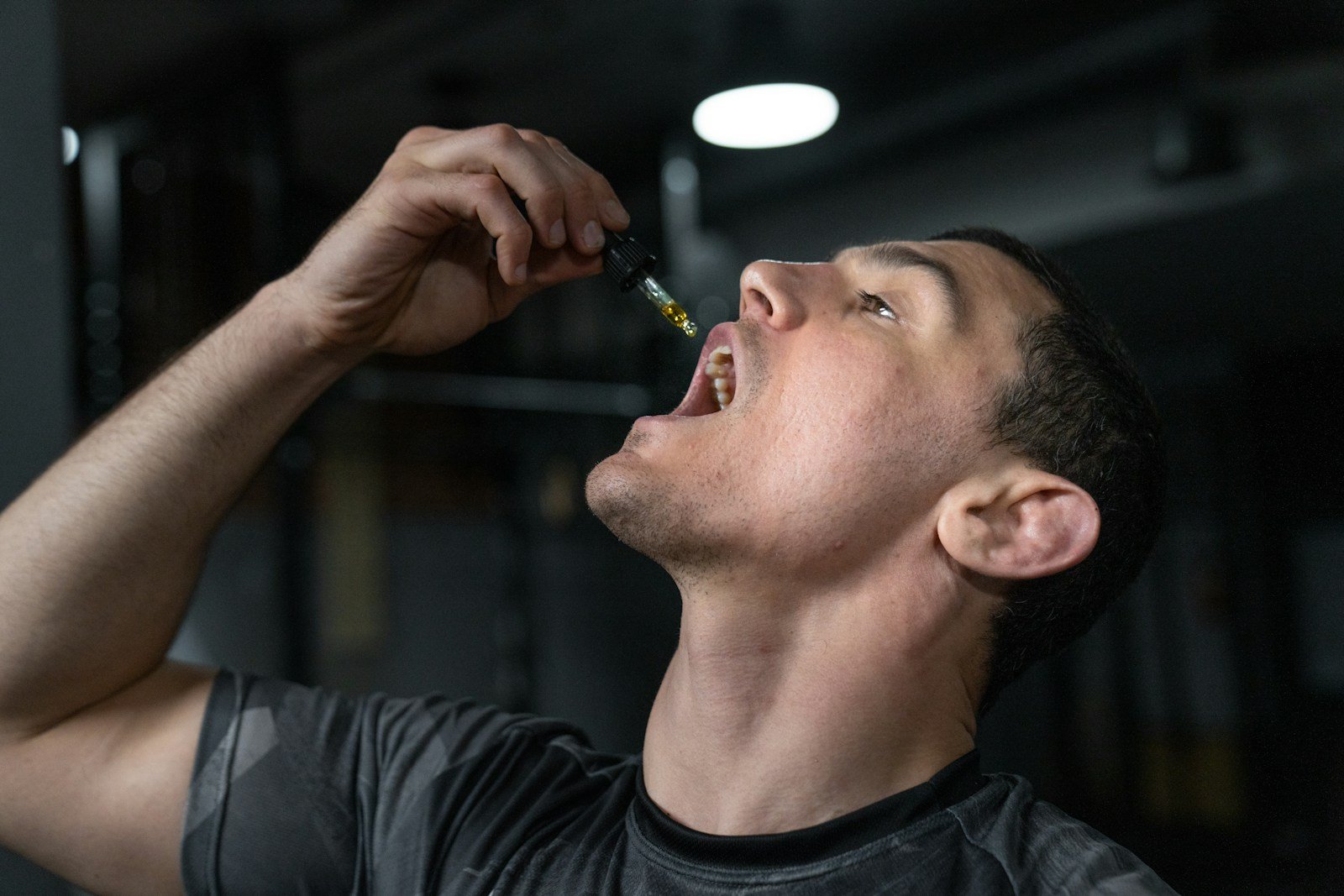 Man taking CBD oil drops with a dropper under his tongue for fast absorption.