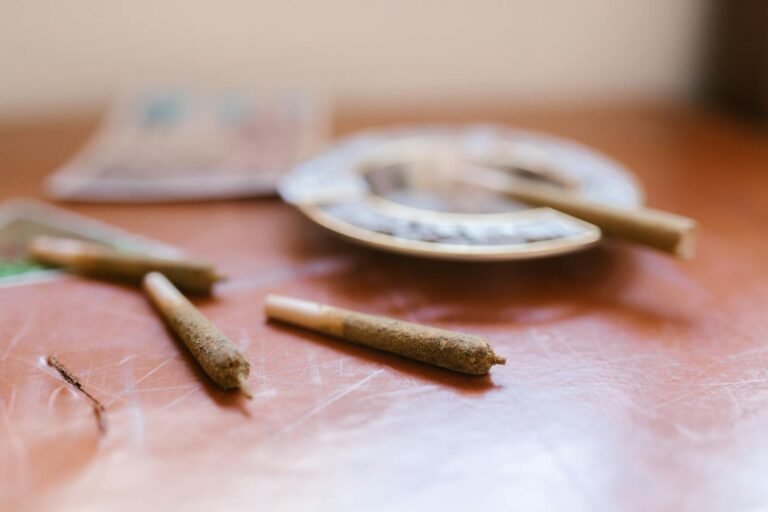 Close-up of rolled cannabis joints on a wooden table near an ashtray