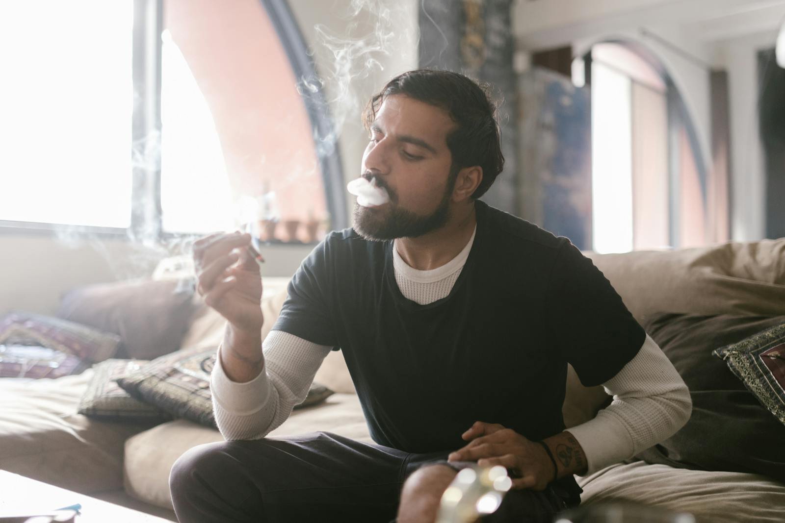 Man smoking a joint indoors while relaxing on a sofa