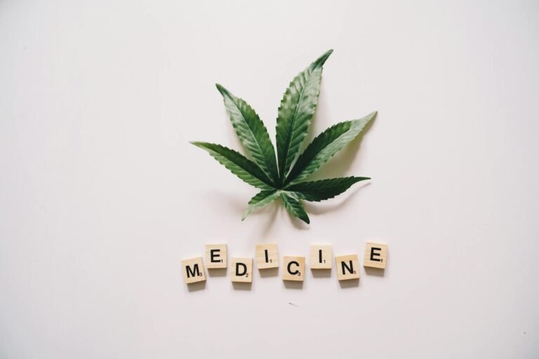Cannabis leaf with wooden blocks spelling “MEDICINE” on white background