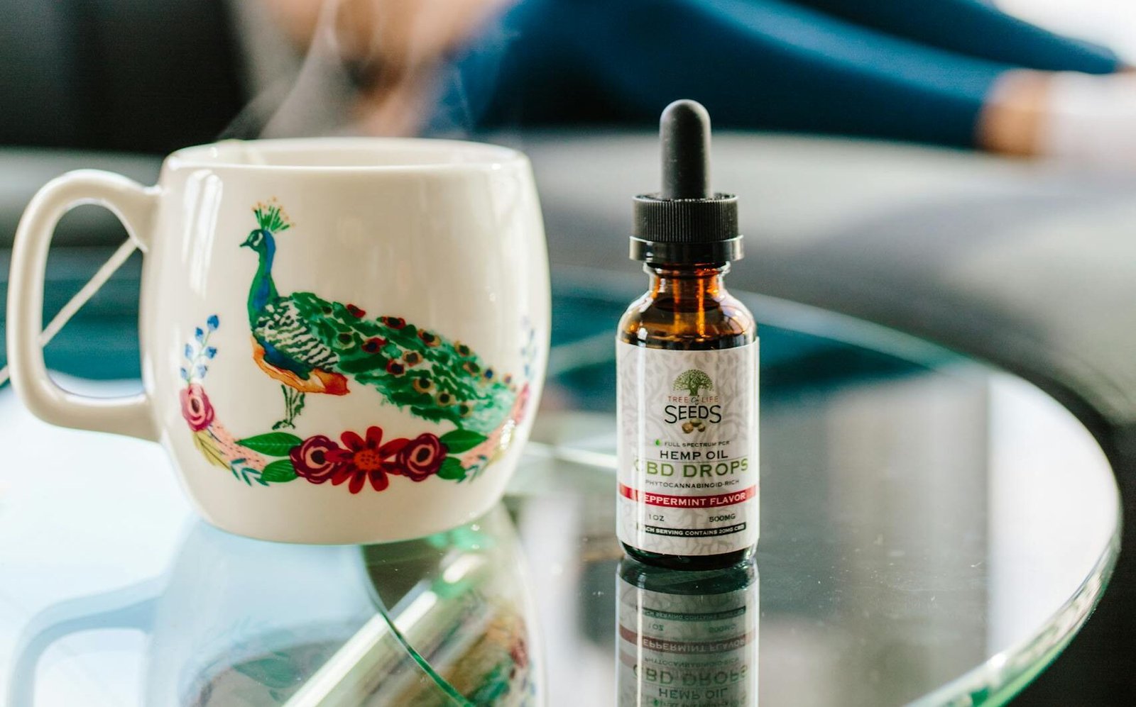 Tree of Life Seeds hemp oil CBD drops bottle next to a decorative mug on glass table