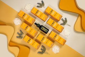 CBD oil dropper bottle with multiple orange premium 1000mg CBD boxes arranged on a yellow background