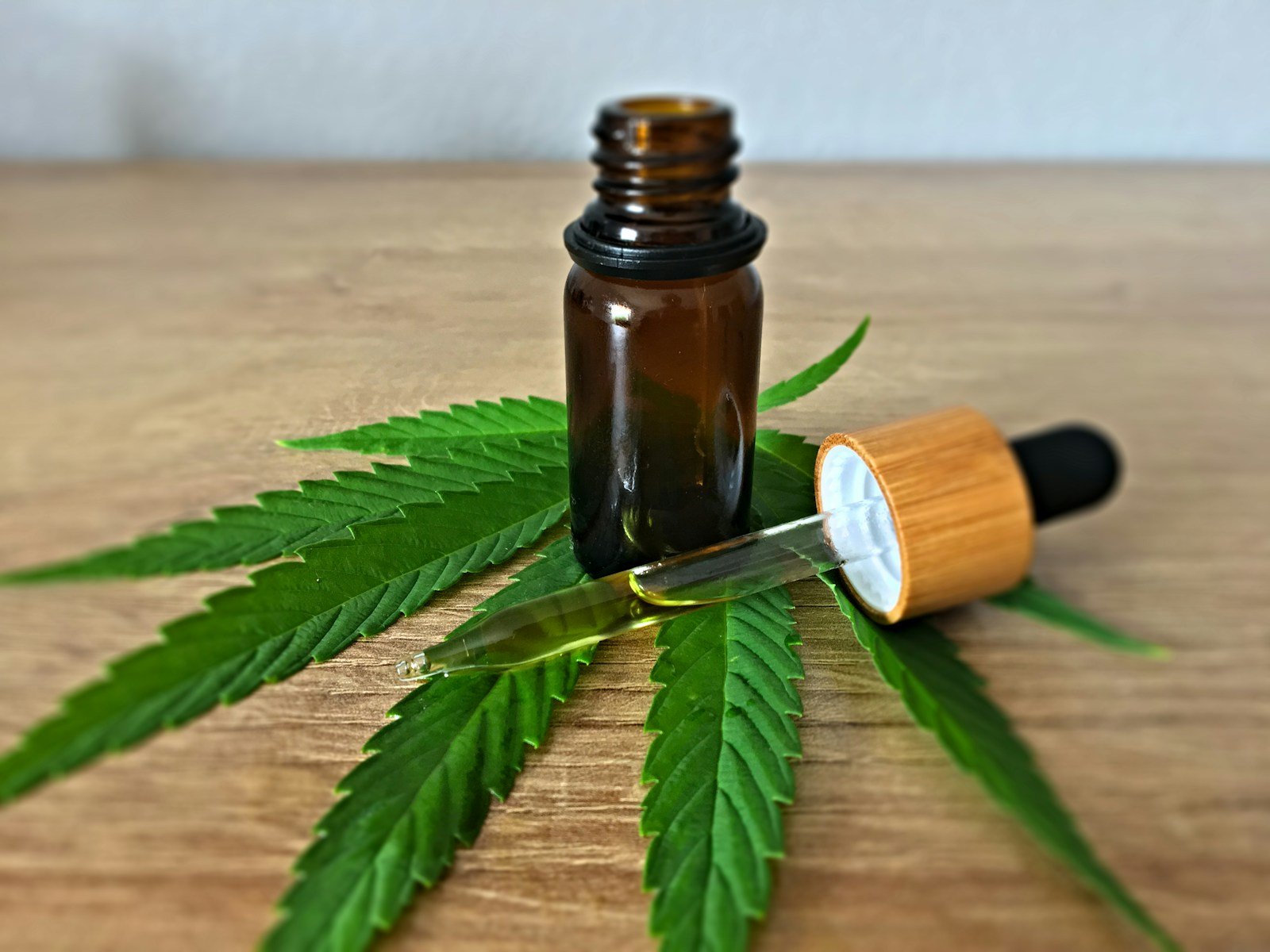 CBD oil bottle with dropper placed on a hemp leaf.
