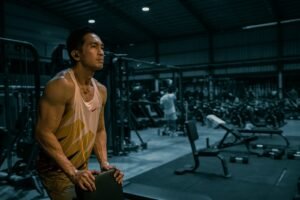 Athletic man in gym resting during workout wearing sleeveless tank top